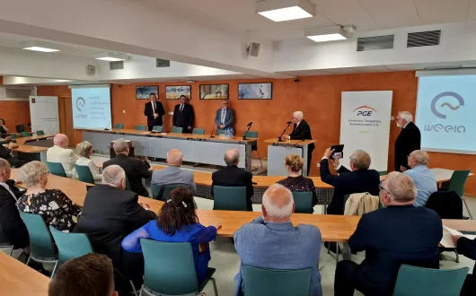 Grupa absolwentów Wydziału Elektrycznego z rocznika 1976 siedząca w sali konferencyjnej podczas uroczystości rozdania Złotych Dyplomów 