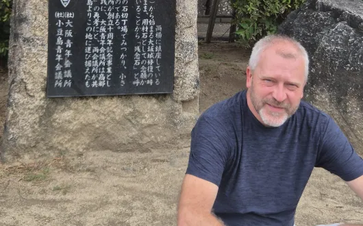 Mężczyzna na tle kamiennej tablicy z japońskimi znakami. W wolnym czasie prof. Paweł Rózga najchętniej podróżuje do krajów Azji