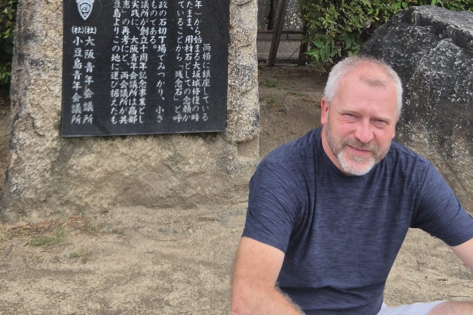 Mężczyzna na tle kamiennej tablicy z japońskimi znakami. W wolnym czasie prof. Paweł Rózga najchętniej podróżuje do krajów Azji