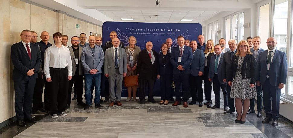 Grupa uczestników konferencji pozuje do pamiątkowego zdjęcia na  korytarzu Wydziału. 