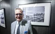 Autor zdjęć na tle czarno-białej fotografii na wystawie w Galerii Pod Napięciem