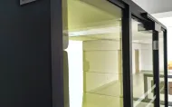 Zdjęcie budki akustycznej dla studentów z antracytową obudową, zielonym wnętrzem, białym blatem stolika. 