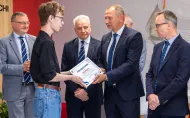 Przewodniczący WRS w imieniu społeczności studenckiej wręcza podziękowanie dla przedstawicieli Hitachi Energy. 