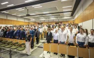 W auli stoi grupa elegancko ubranych studentów, którzy składają ślubowanie.