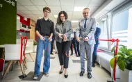 Kobieta i dwóch mężczyzn przecinają czerwoną wstęgę symbolicznie otwierając strefę dla studentów. 
